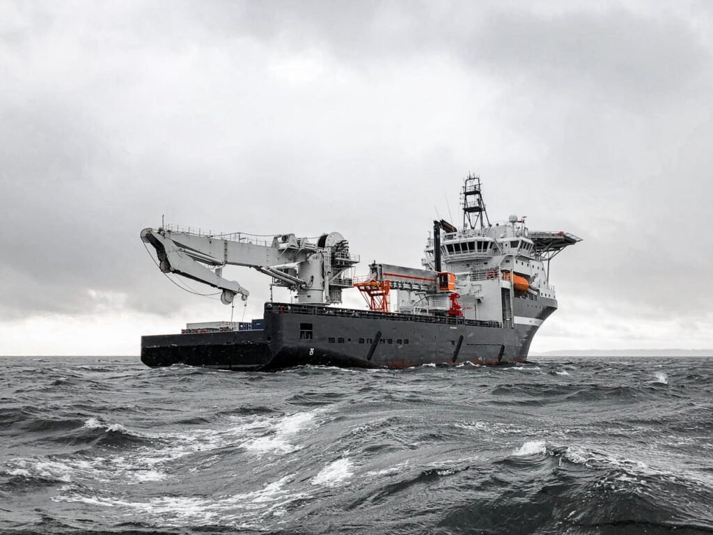 A large industrial ship cruising through a stormy sea under a cloudy sky, showcasing marine engineering and transportation.